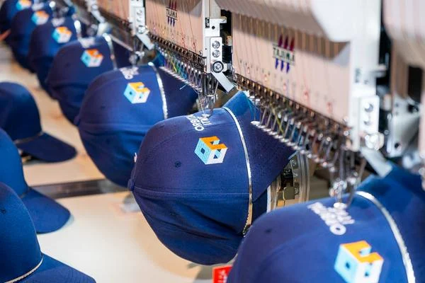 Máy thêu vi tính Tajima đang thêu logo lên nón tại xưởng PHOCO